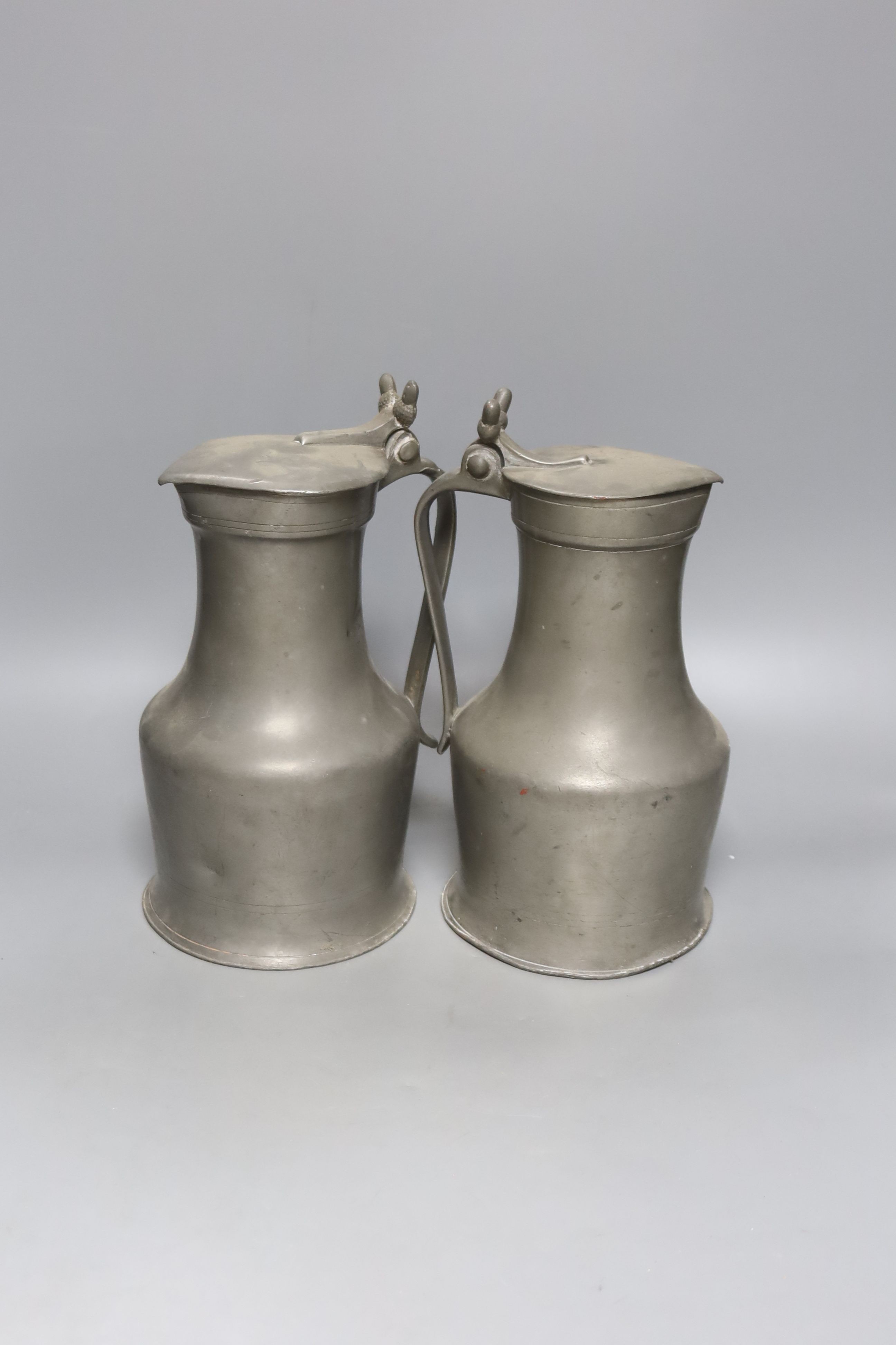 An 18th century French lidded pewter jug with double acorn thumbpiece and another similar jug, tallest 27cm